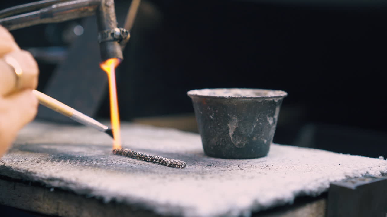 человек наносит материал на нагретую цепь на асбест вблизи