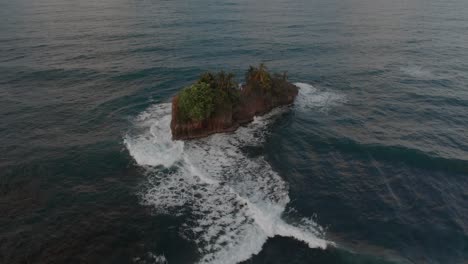 waves crashing on the small rocky island at the caribbean sea in puerto viejo, costa rica - aerial shot