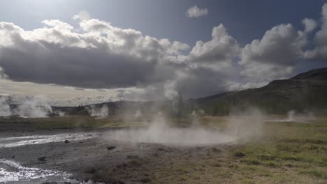 paisaje geotérmico islandés, erupción de géiseres, nubes por encima