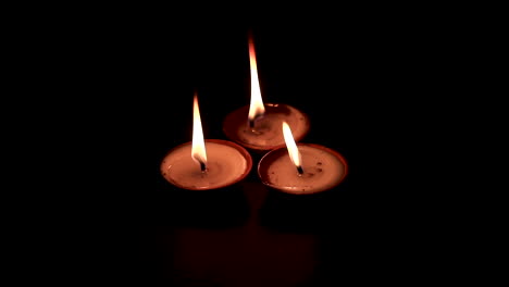three butterlamp candles burning in the dark. traditional butterlamp glowing in the dark