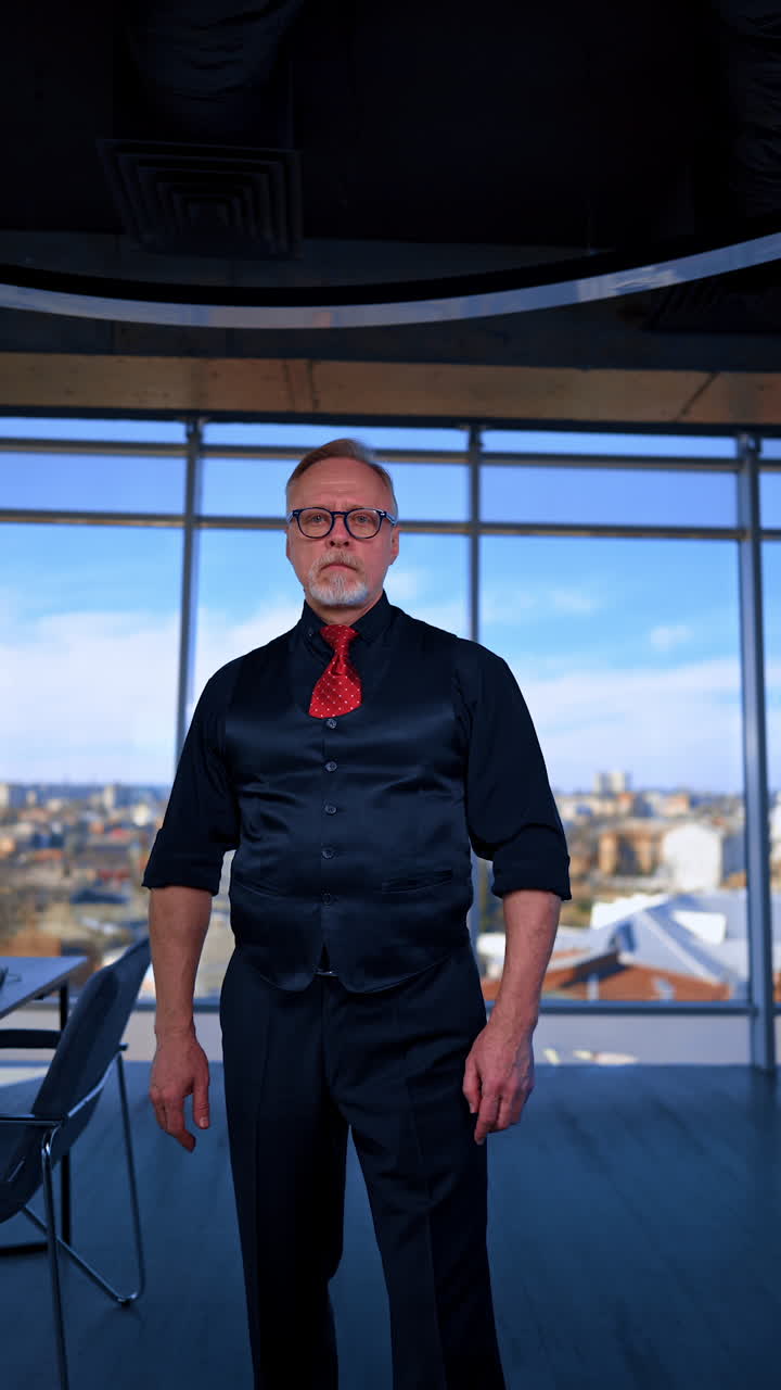 Adult Caucasian male in black shirt, vest and trousers and red tie in office gestures to camera. Boss is telling off employees or tries to convince in something. Vertical video.