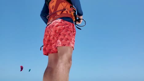 man-wears-red-helmet-kitesurf-equipment-on-the-beach-ready-to-kiting,-tilt-down