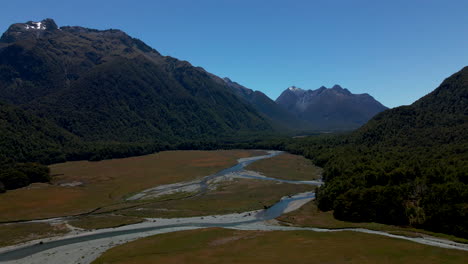 Blue-river-making-its-way-down-the-hill-in-mountain-valley-in-Fiordland-Southland,-New-Zealand