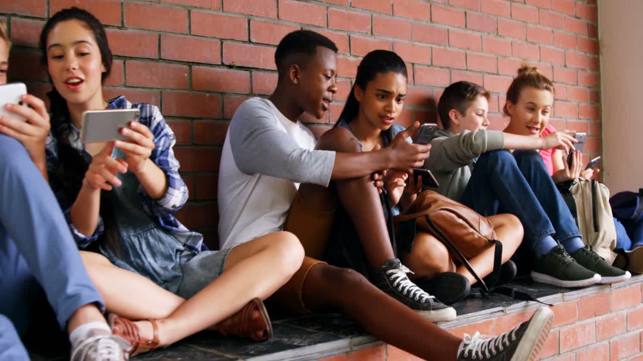 grupo de amigos de la escuela usando teléfono móvil 4k