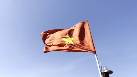 red flag with gold star flapping in the wind with blue sky, vietnam