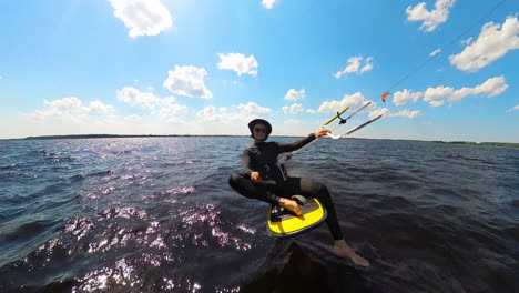 a man kiteboards across choppy waters under a bright, cloud-dotted sky on a windy day - tracking shot