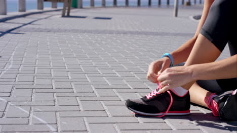 mujer corredora atando el cordón de su zapato antes de su carrera de paseo