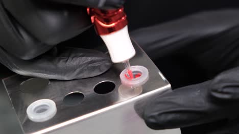 close-up of a tattoo artist preparing red ink for a procedure