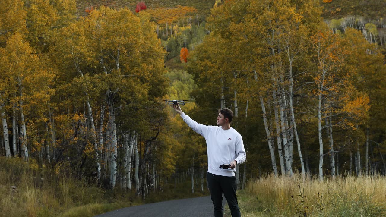 현대 드론은 가을 색 ⁇ 의 숲에서 젊은 남자의 손을  ⁇ 습니다.
