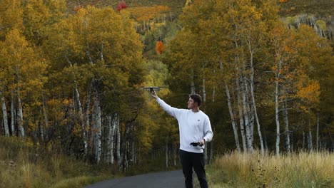 Moderne-Drohne-Nimmt-Einem-Jungen-Mann-Im-Herbstlich-Gefärbten-Wald-Die-Hand-Ab