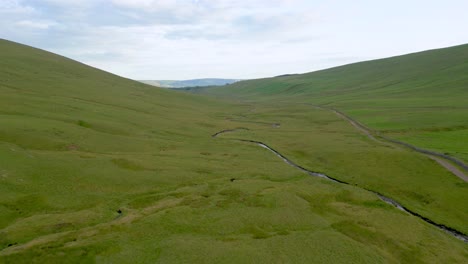 River-and-country-road-in-Welsh-hills,-aerial-flypast