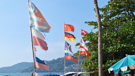 national flags waving at patong beach, phuket, with a clear view of the coastline