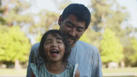 Porträt-Eines-Glücklichen-Asiatischen-Vaters,-Der-Die-Kleine-Tochter-Im-Freien-Kitzelt