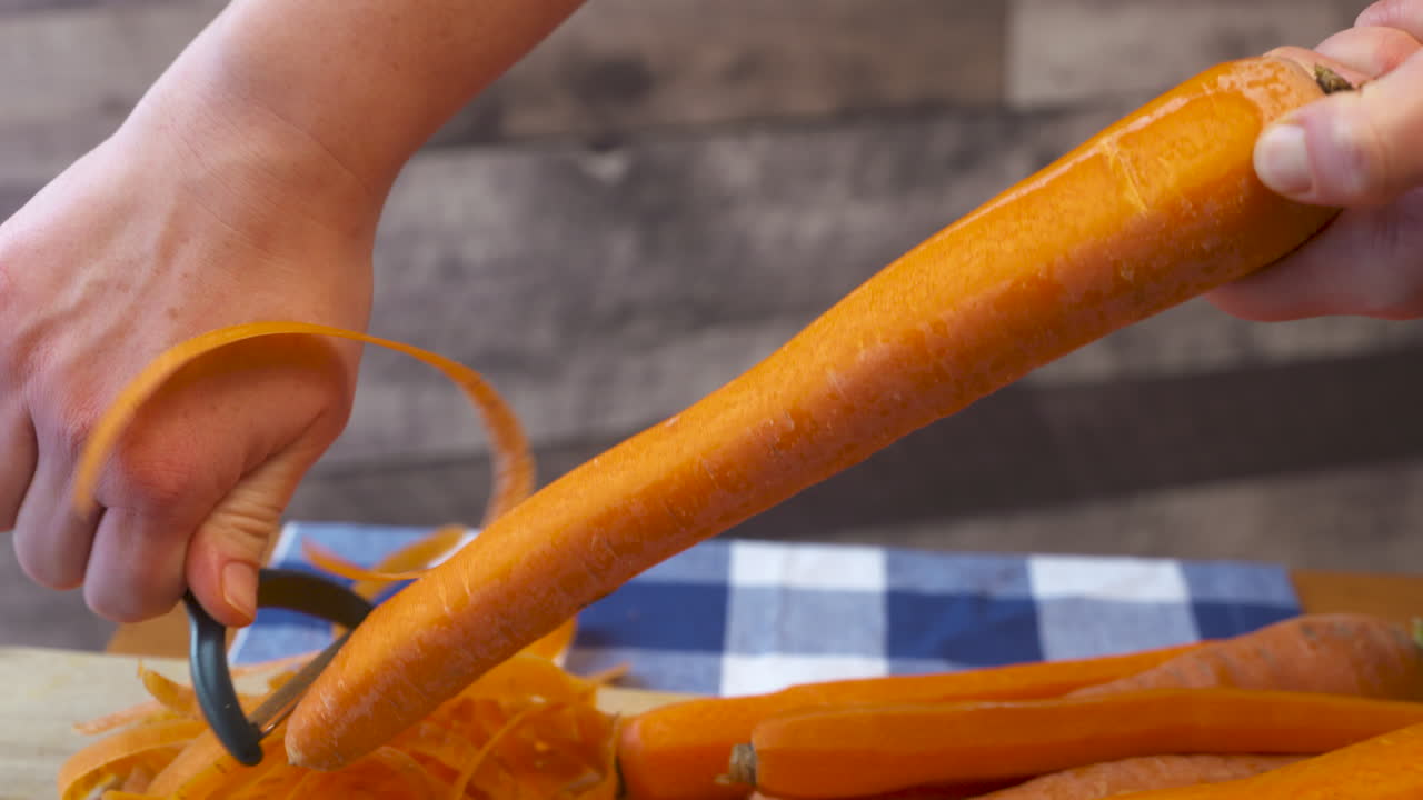 Mano che sbuccia una carota intera e croccante.