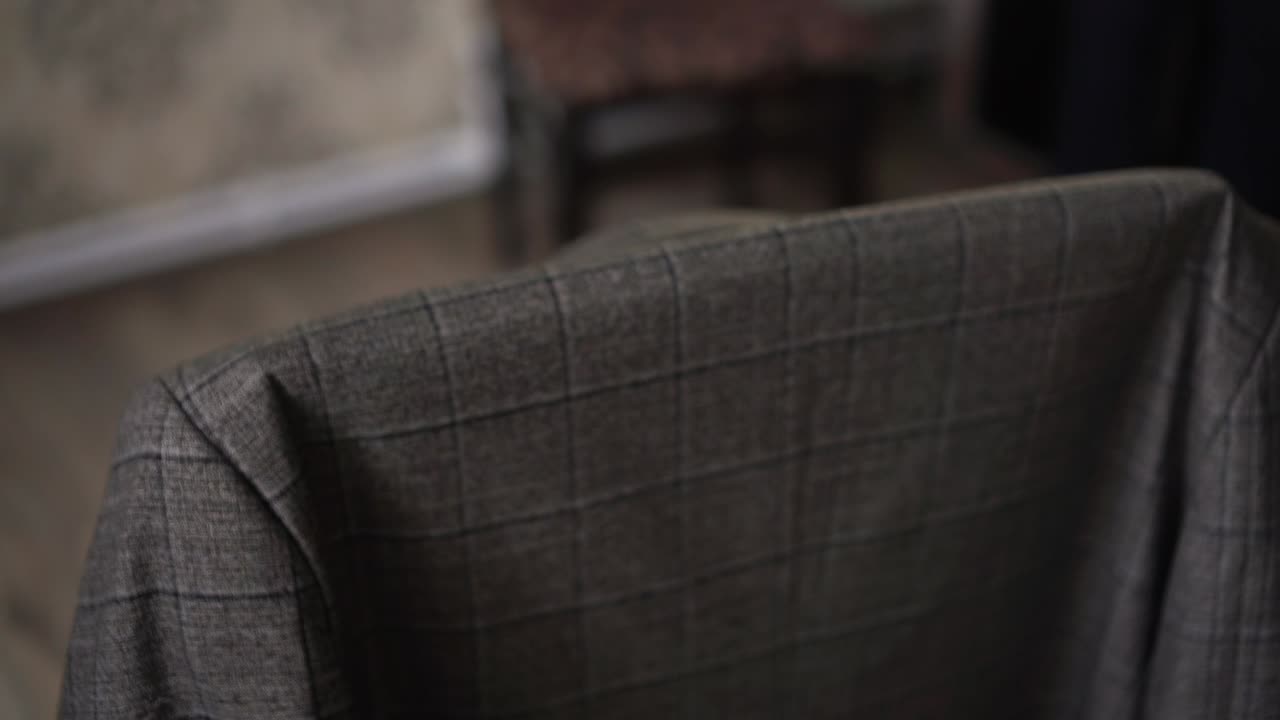 un hombre toma una chaqueta gris de una silla