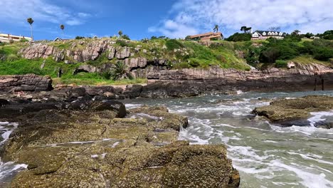 waves crashing against the punta ballena cliffs, showing mansions on top of the hill, in uruguay