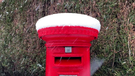 A-red-post-mailbox-in-winter-at-christmas-covered-with-snow