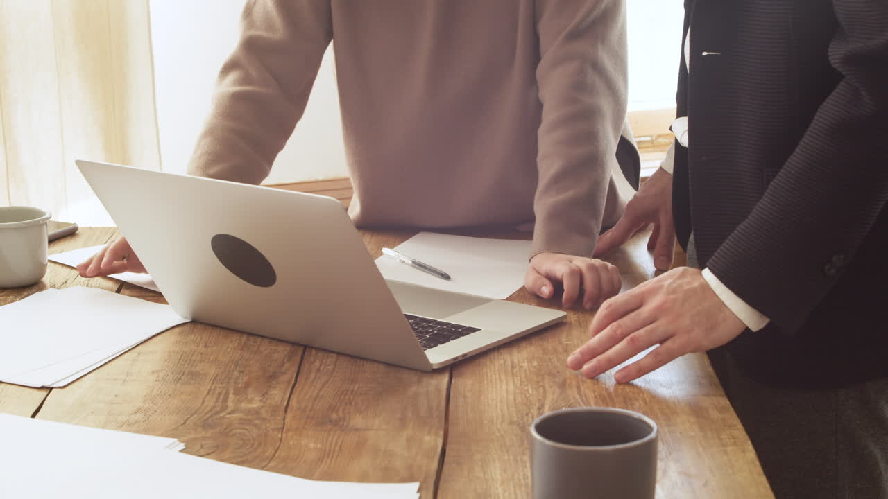 탁자 위에 있는 노트북 컴퓨터를 보면서 토론하는 알아볼 수 없는 두 동료