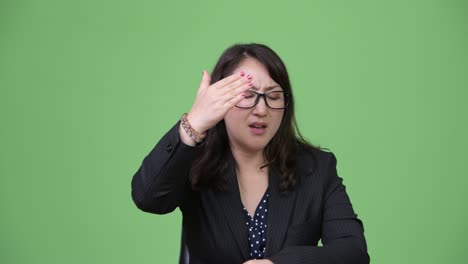 mature beautiful asian businesswoman having headache while sitting behind desk