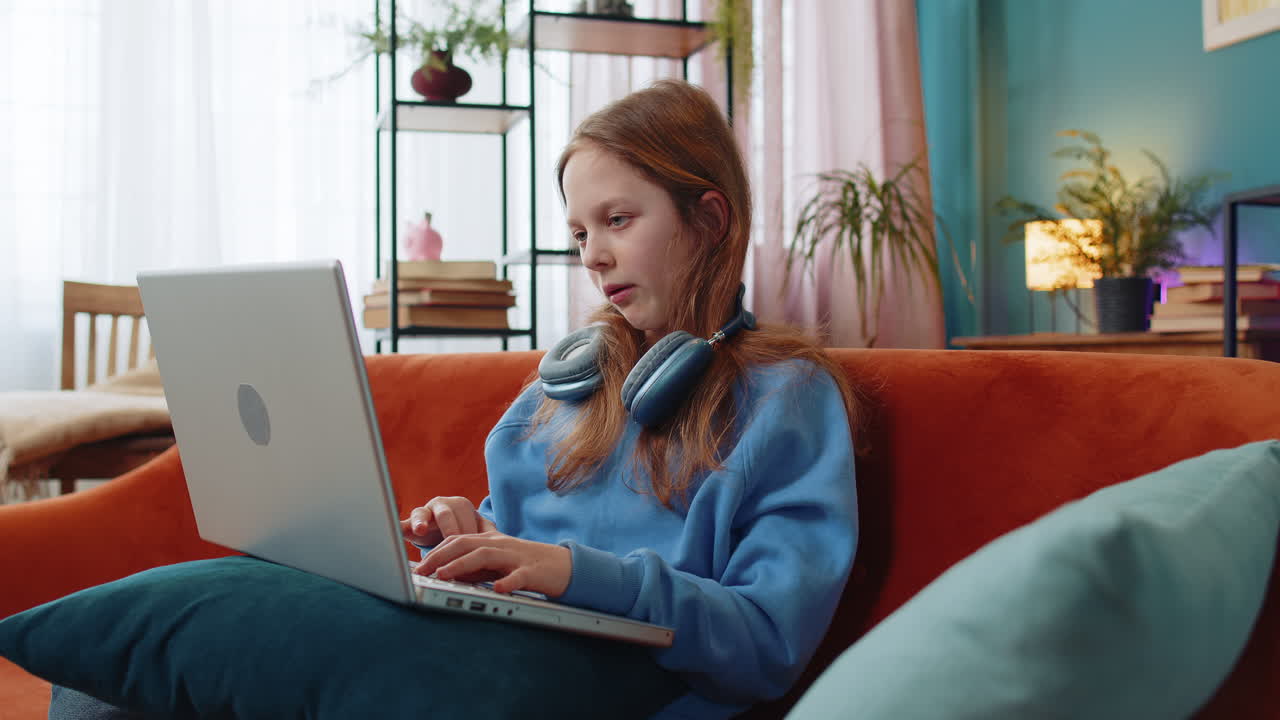 Overtired caucasian teenage child girl bored using laptop doing a education project types lazily