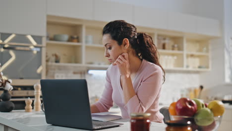 chica enfocada estudiando en línea en casa cocina de cerca. mujer estudiante tomando notas