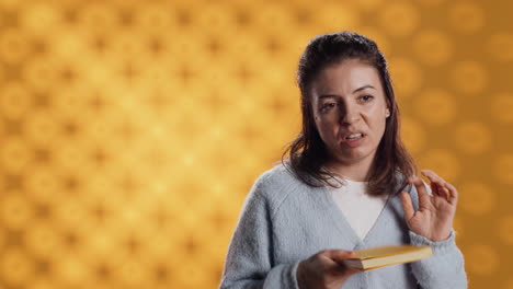 Disappointed-woman-bashing-book,-showing-thumbs-down-sign,-studio-background