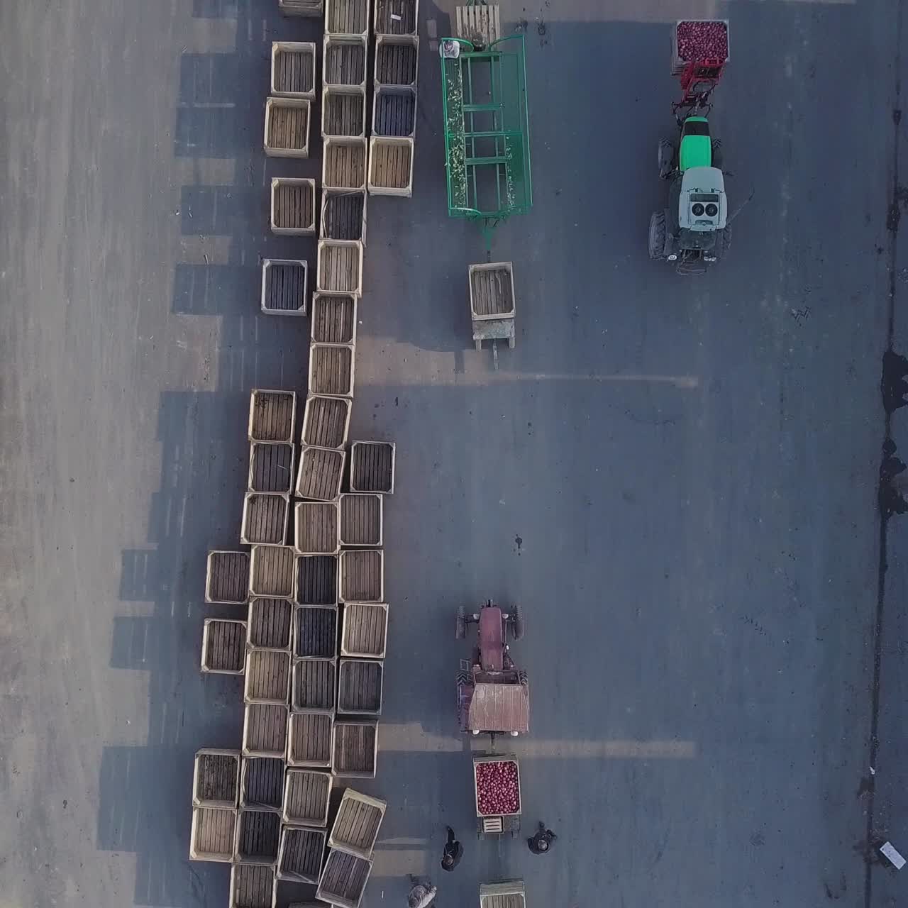 warehouse workers are preparing an empty crate for apples. Loader is relocating pallet with apples in the territory of warehouse for further transportation to the plant for the production of juice. Aerial view