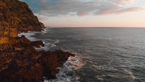 altas olas lavan los acantilados de la playa de piha que están pintados en colores cálidos en la hora dorada