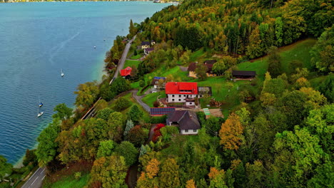 Drone-shot-of-flying-by-the-lake-shore-with-thick-dense-forest-and-houses-cottages-in-between-the-trees