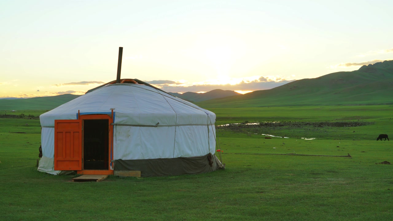 Traditionell mongolisk jurta på grön gräsmark vid solnedgången