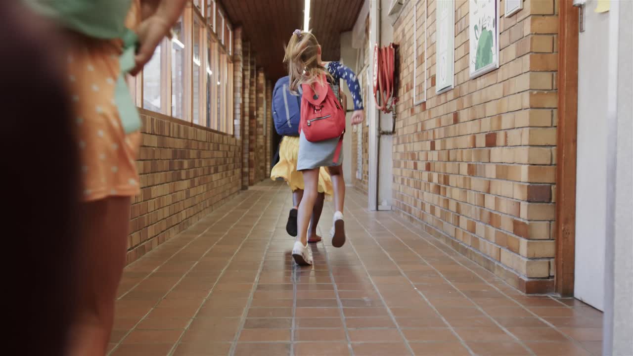 초등학교 의 복도 에서 달리는 학교 가방 을 들고 있는 행복 한 다양 한 여학생 들 의 뒷면