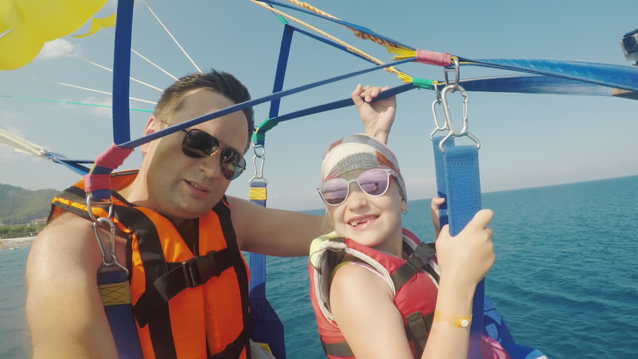 padre e hija vuelan en parasailing un padre se toma una selfie con una chica unas vacaciones activas wi