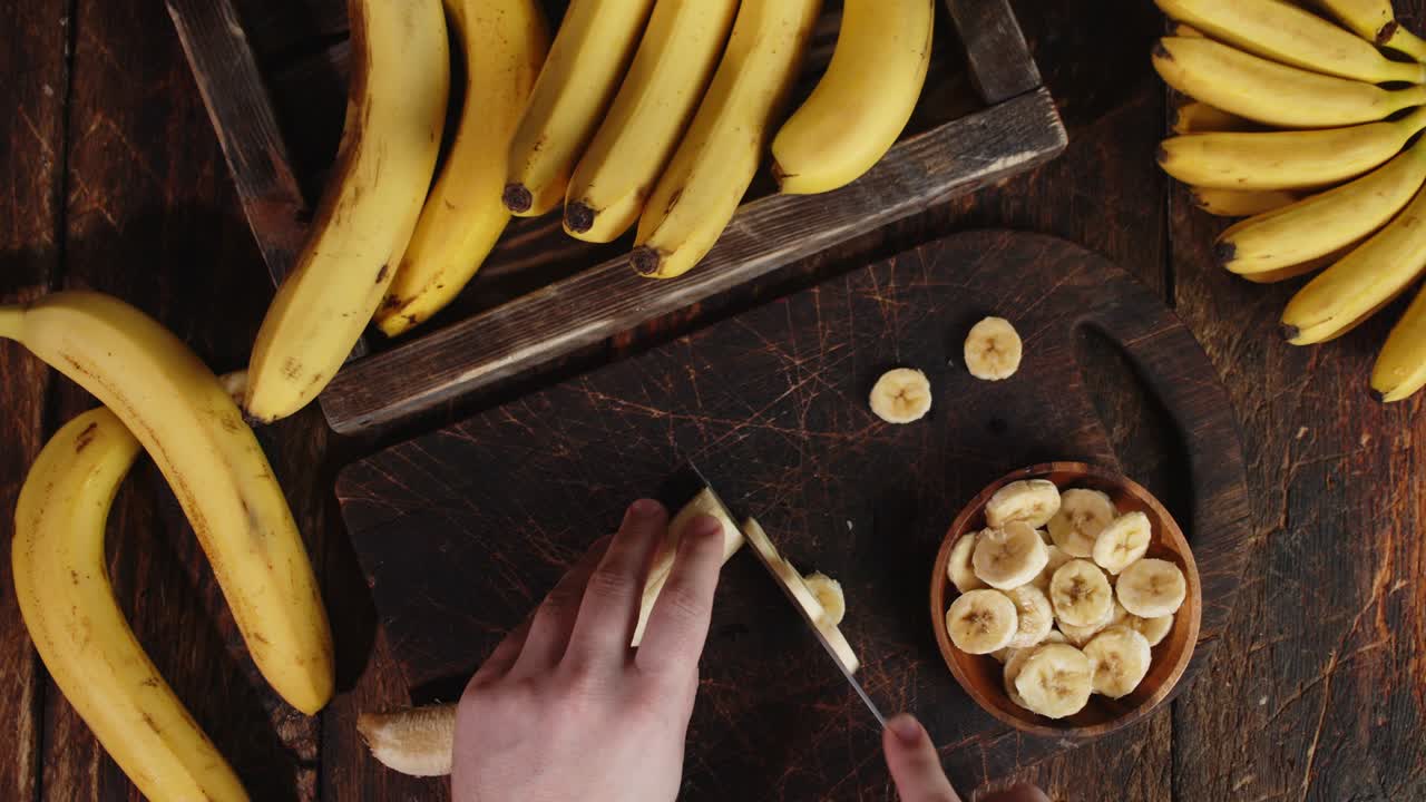 Male hands slicing the banana on a cutting Board.