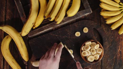 male hands slicing the banana on a cutting board.