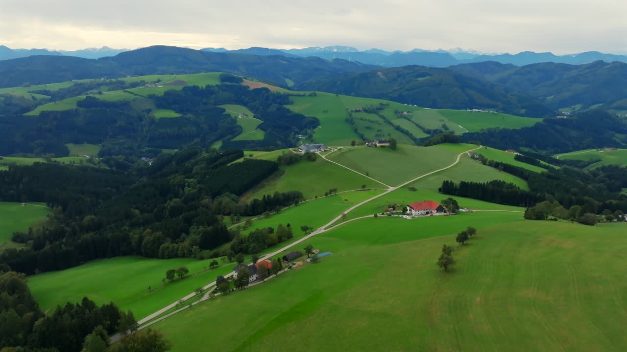 Scenic aerial over green alpine pastures and scattered homes in Kürnberg, Austria