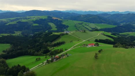 scenic aerial over green alpine pastures and scattered homes in kürnberg, austria
