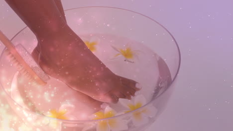 animation of light spots over african american woman washing feet