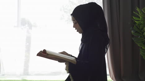 an asian muslim woman reciting salah or salat al-fatiha passage of the qur'an, in a single act of sujud called a sajdah or prostrations at home