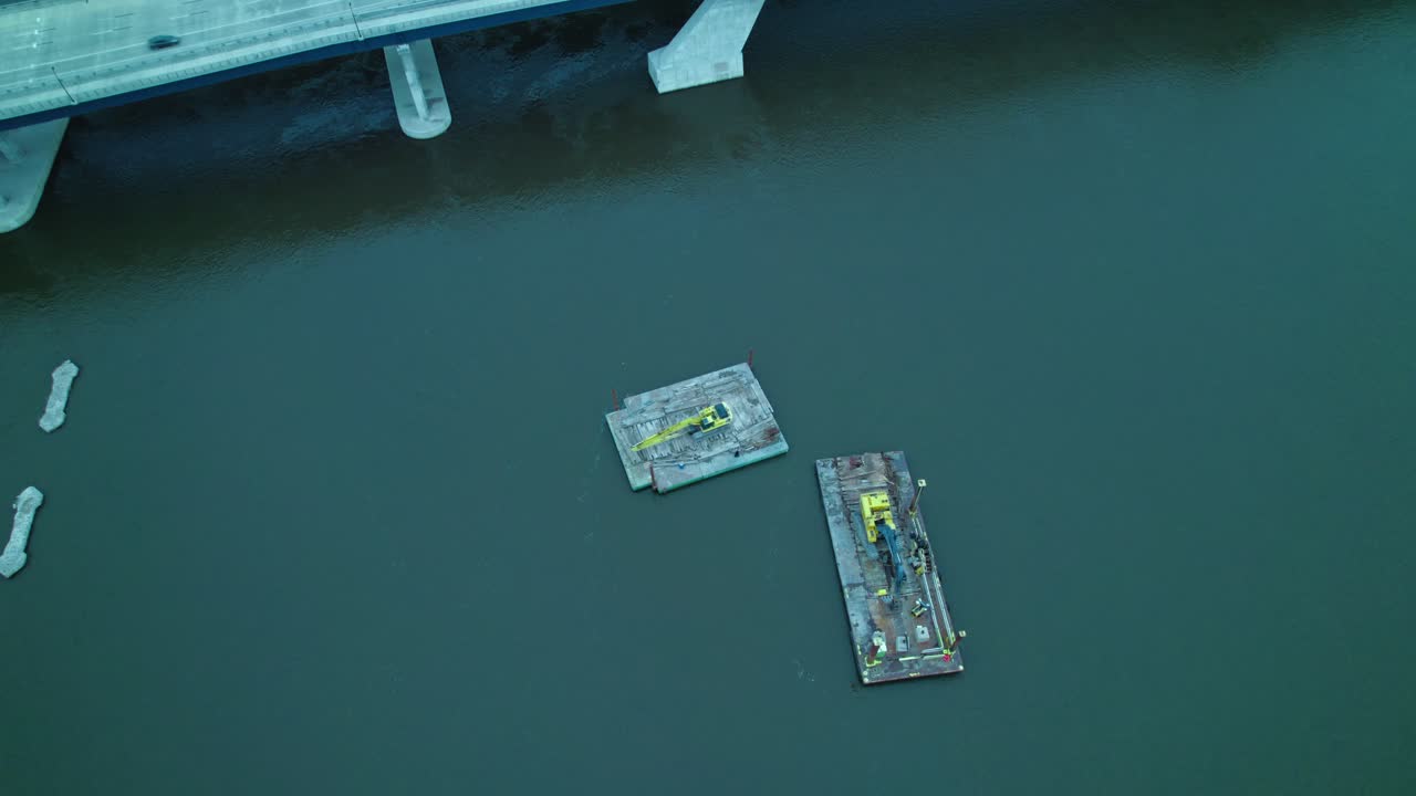 Excavators on floating dock pontoon on mississippi river near Centennial Bridge in Davenport, Iowa, USA