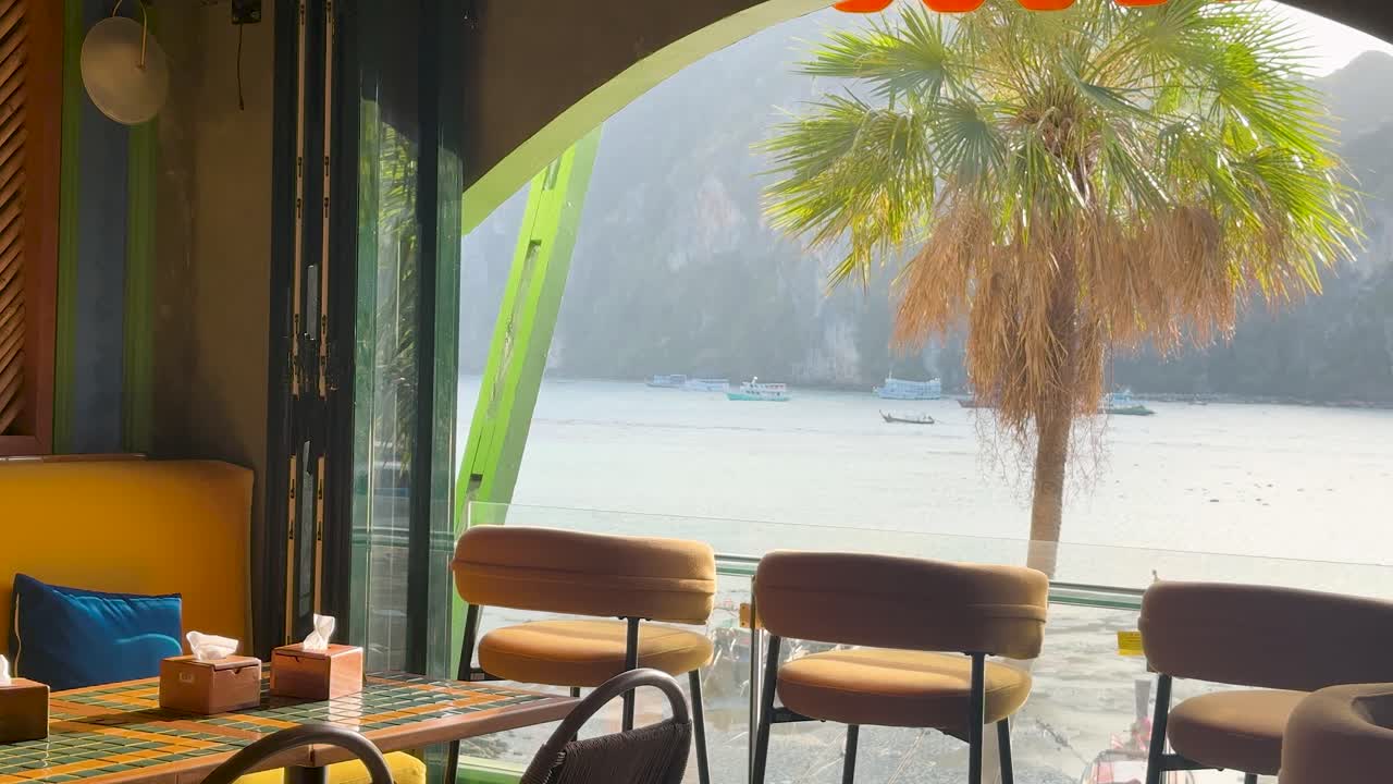 Inquadratura grandangolare statica dell'interno vuoto di un ristorante tropicale con vista su una baia insulare panoramica.