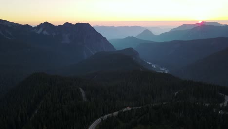 Drone-captures-an-aerial-shot-of-Mount-Rainier-National-Park-and-in-the-background-as-the-sun-rises-from-the-horizon