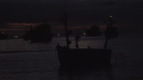 vista nocturna de una playa en vietnam con filas de botes con luces de emergencia parpadeando sobre ellos.