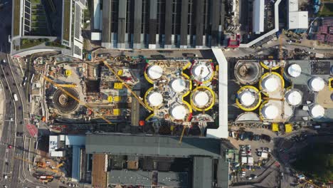 Aerial-top-down-view-of-huge-construction-site-of-main-train-station-Stuttgart-S21-with-cranes-and-construction-worker-flying-left-to-right-in-Stuttgart,-Germany