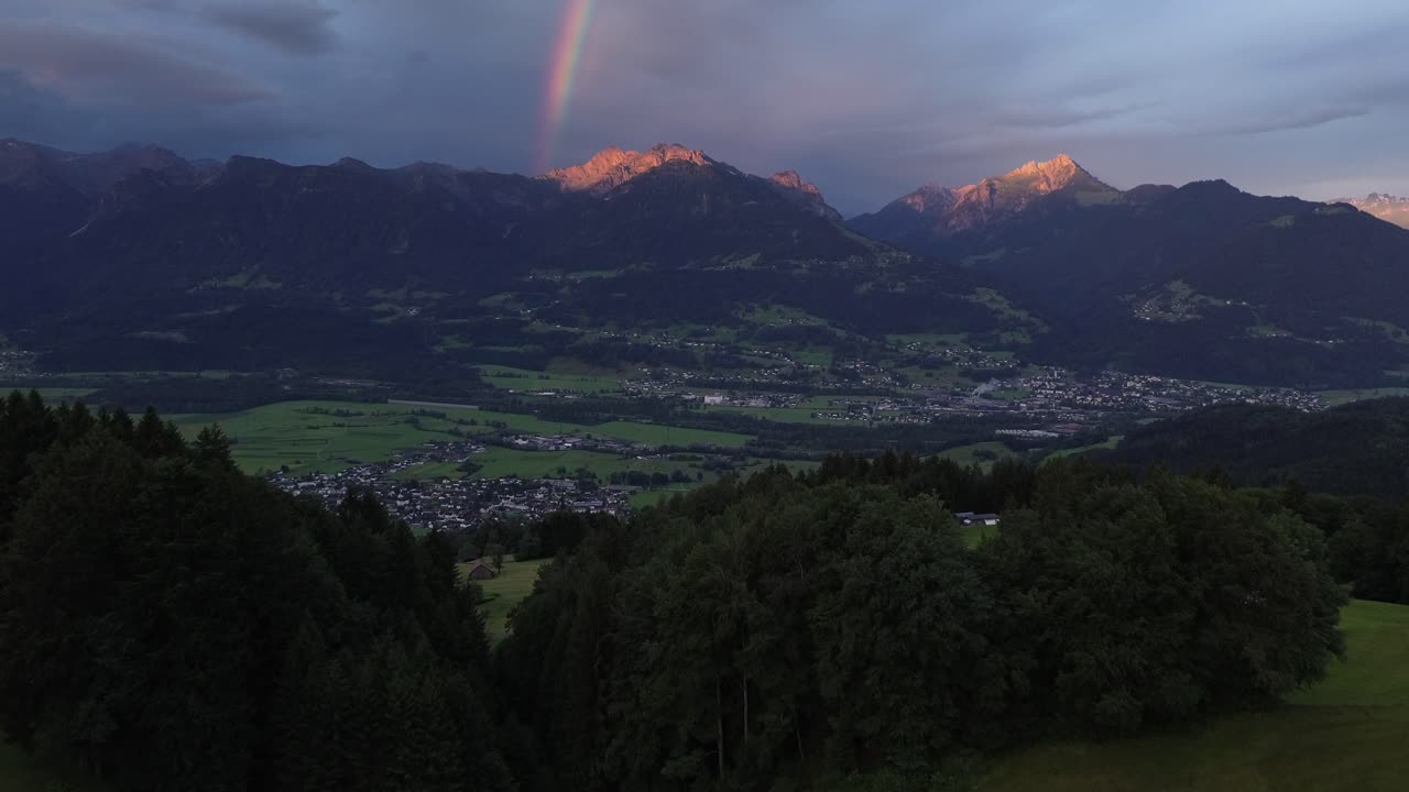 Aerial view of Sunrise behind Mountain Range in Austria with Rainbow in Background