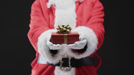 Video-of-santa-claus-holding-christmas-present-with-copy-space-on-black-background