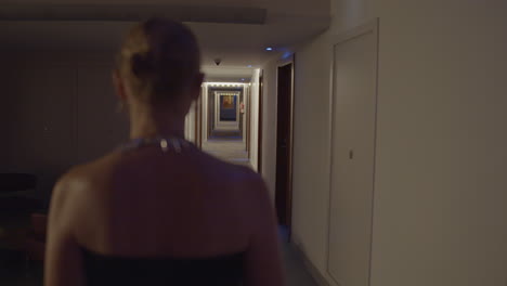 woman walking down a hotel corridor at night