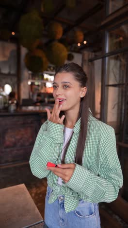 mujer aplicando lápiz labial en un café