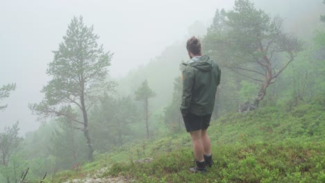 man drinking a hot coffee or tea standing on a mountainside covered with morning fog