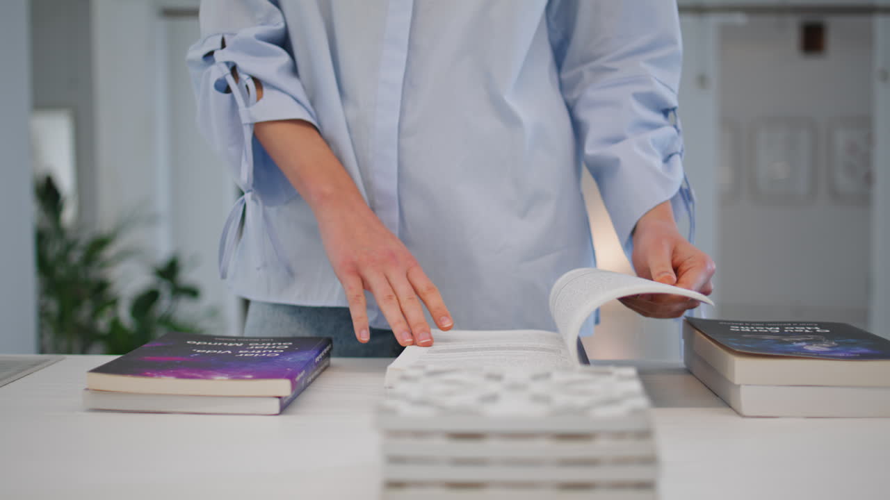 las manos de la mujer seleccionan el libro en la exhibición de primer plano. visitante de la librería girando las páginas