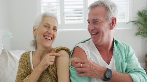 Happy-caucasian-senior-couple-showing-plasters-after-vaccination